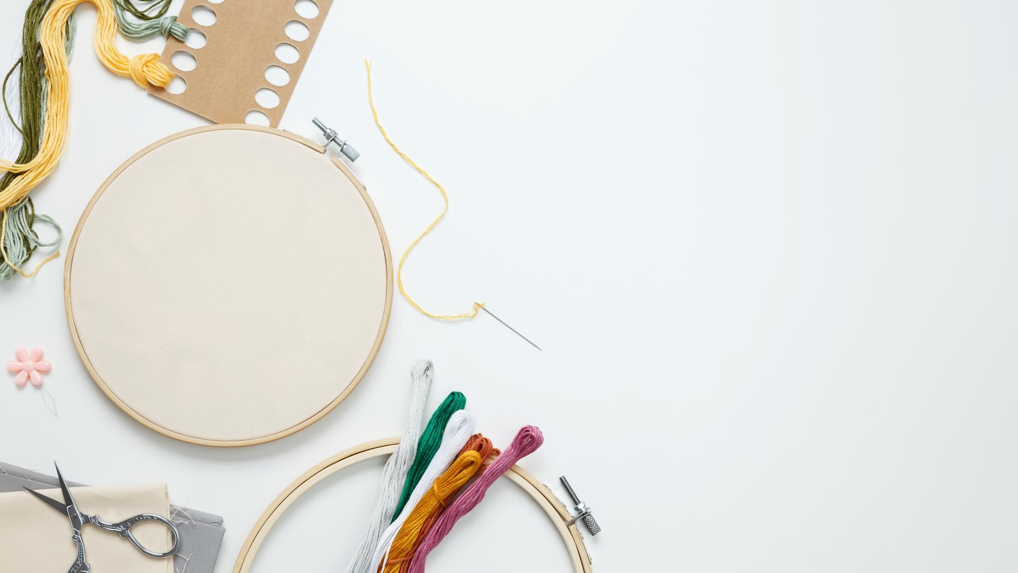 Studio table with embroidery hoop and threads in cool palette